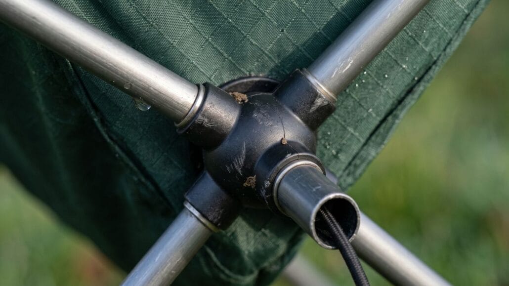 Campingstol — sådan vælger du den rigtige foldestol 12 Makro af campingstolens sorte hub hvor alu-rør og elastik-snor mødes