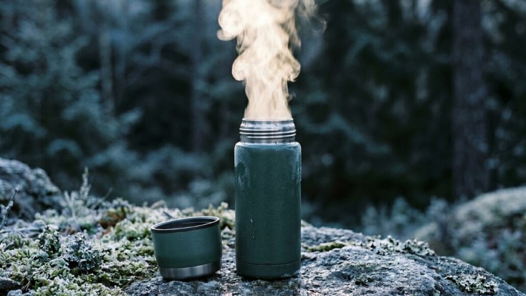 Drikkedunk og termoflaske til outdoor — sådan vælger du den rigtige 4 Mørkegrøn termoflaske med dampende varm drik på en frostdækket sten