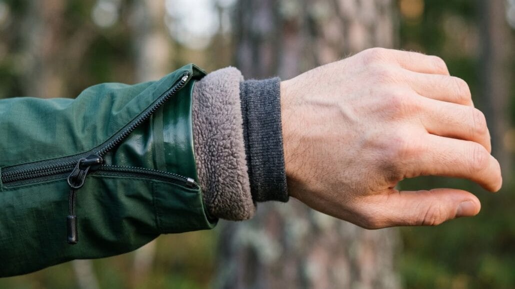 Tre lag på en arm: grøn skal, grå fleece og strikket inderlag