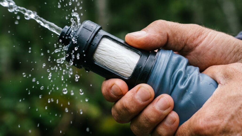 Vandfilter til vandring — sådan renser du vand på turen 15 To hænder backflusher et vandfilter ved en bæk